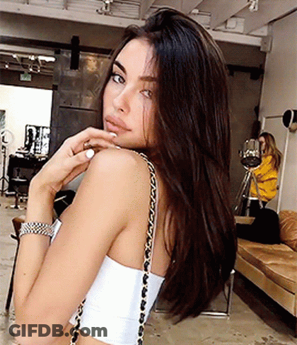 A Woman Wearing A White Crop Top With A Gold Chain Shoulder Strap GIF