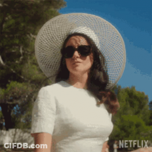 A Woman Wearing A White Dress And A White Hat And Sunglasses . GIF