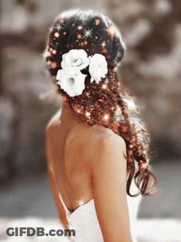 A Woman Wearing A White Dress Has Flowers In Her Hair GIF