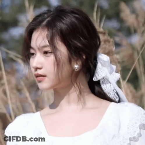 A Woman Wearing A White Dress With A Bow In Her Hair GIF
