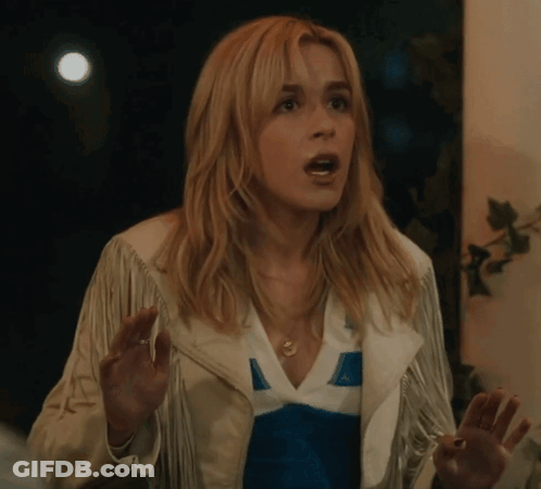A Woman Wearing A White Fringed Jacket And A Blue And White Shirt Is Making A Surprised Face GIF