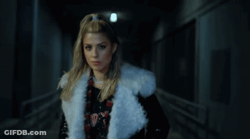 A Woman Wearing A White Fur Coat And A Plaid Shirt With The Word Nirvana On It GIF