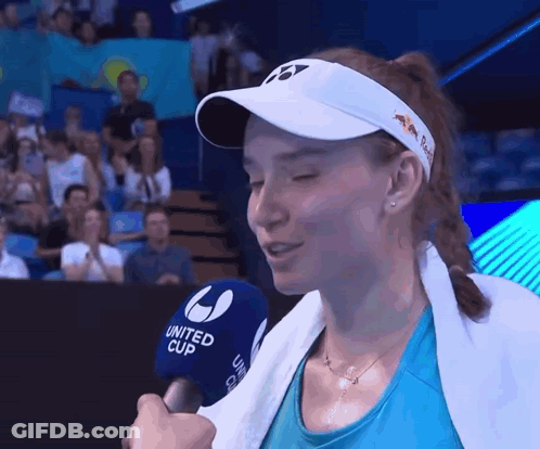 A Woman Wearing A White Hat And A Blue Shirt Is Talking Into A United Cup Microphone GIF