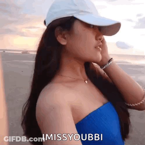 A Woman Wearing A White Hat And A Blue Top Says I Miss Youbbi GIF