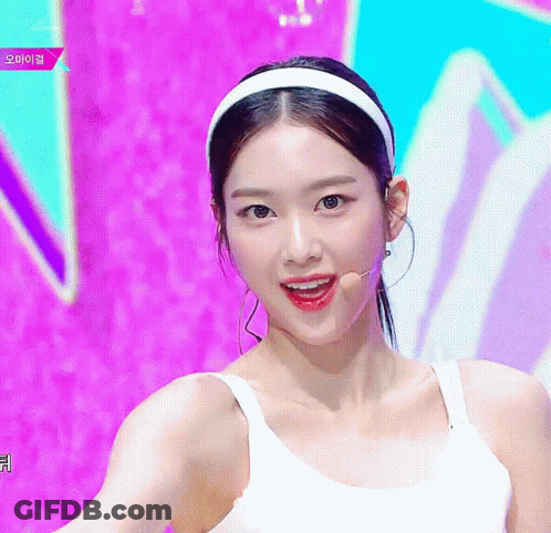 A Woman Wearing A White Headband And A White Tank Top Is Smiling GIF