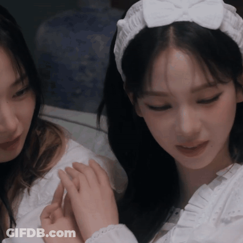 A Woman Wearing A White Headband With A Bow Is Holding Another Woman 'S Hand GIF