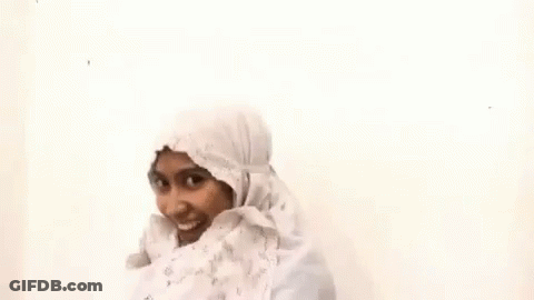 A Woman Wearing A White Hijab And A White Dress Is Smiling . GIF