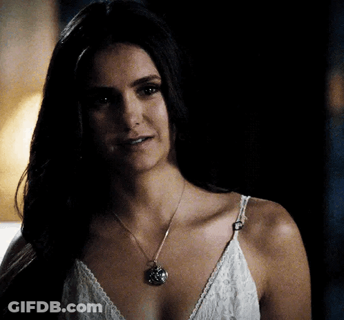 A Woman Wearing A White Lace Top And A Necklace GIF