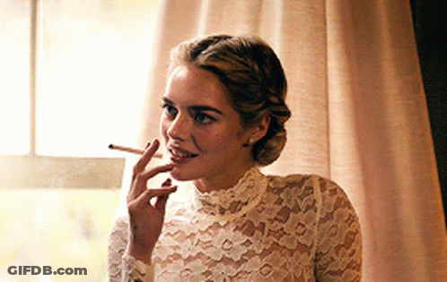 A Woman Wearing A White Lace Top Is Smoking A Cigarette GIF