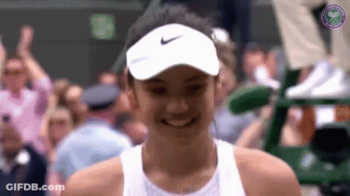 A Woman Wearing A White Nike Hat Smiles In Front Of A Crowd GIF