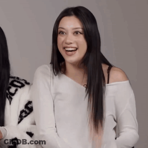 A Woman Wearing A White Off The Shoulder Sweater With The Letters Cc On It GIF