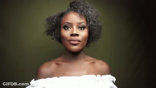A Woman Wearing A White Off The Shoulder Top Is Looking At The Camera GIF