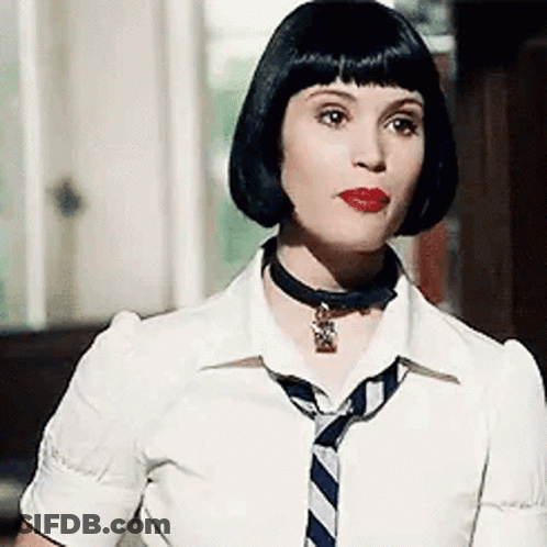 A Woman Wearing A White Shirt And A Blue And White Striped Tie Is Standing In Front Of A Window . GIF