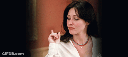 A Woman Wearing A White Shirt And A Necklace With A Heart On It GIF