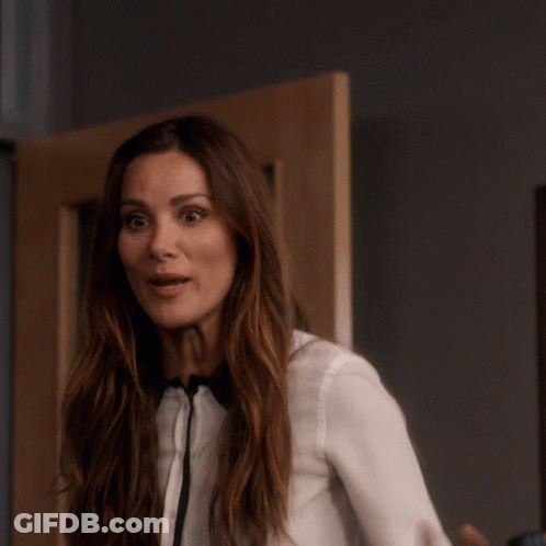 A Woman Wearing A White Shirt And Bow Tie Is Pointing At The Camera GIF
