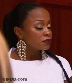 A Woman Wearing A White Shirt And Earrings Is Looking Down . GIF