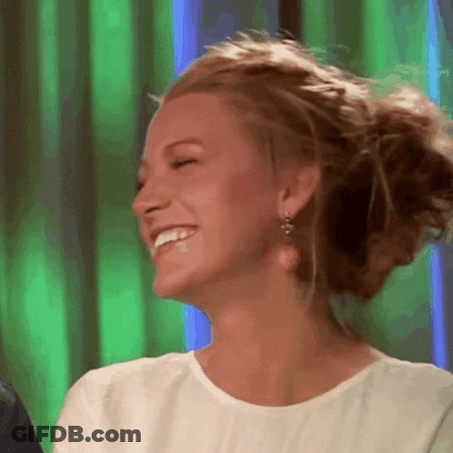 A Woman Wearing A White Shirt And Earrings Smiles With Her Eyes Closed GIF