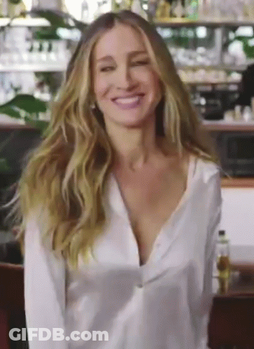 A Woman Wearing A White Shirt Is Smiling And Looking At The Camera GIF