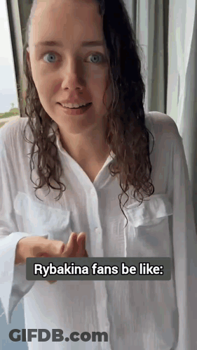 A Woman Wearing A White Shirt Is Standing In Front Of A Window With The Caption Rybakina Fans Be Like GIF