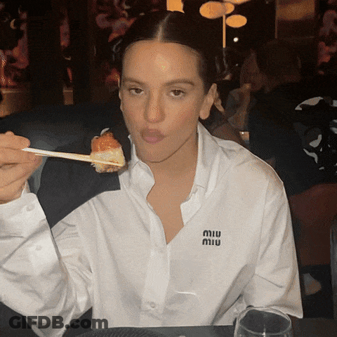 A Woman Wearing A White Shirt With A Miu Logo On It GIF