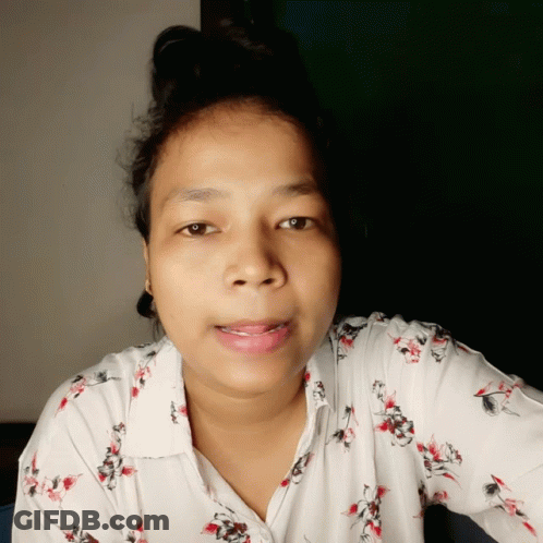 A Woman Wearing A White Shirt With Red And Black Flowers GIF