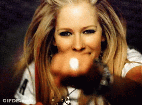 A Woman Wearing A White Shirt With The Letter A On It Is Pointing At The Camera GIF