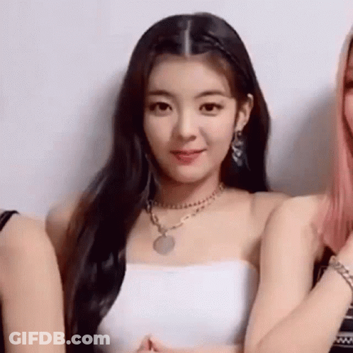 A Woman Wearing A White Strapless Top And A Necklace Is Standing Next To Two Other Women . GIF