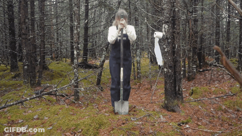 A Woman Wearing A White Sweater And Black Apron Has The Letter T On Her Apron GIF