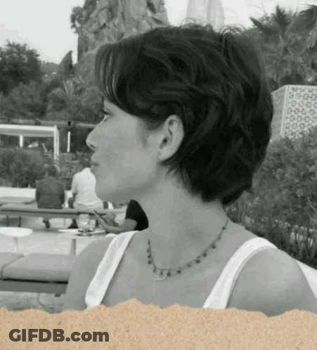 A Woman Wearing A White Tank Top And A Necklace GIF
