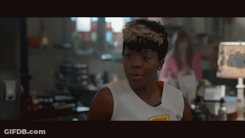 A Woman Wearing A White Tank Top With A Yellow Letter T On The Front GIF