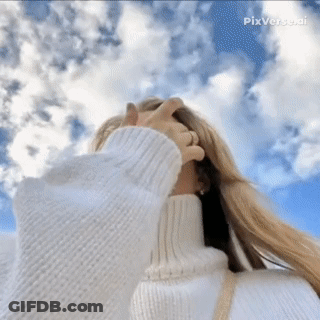 A Woman Wearing A White Turtleneck Sweater Covering Her Face With Her Hand GIF