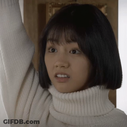 A Woman Wearing A White Turtleneck Sweater Looks Surprised GIF