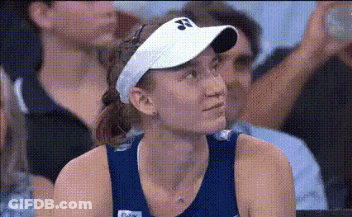 A Woman Wearing A White Visor Is Sitting In A Crowd . GIF