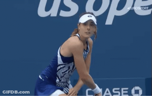 A Woman Wearing A White Visor Is Standing In Front Of A Sign That Says Uop GIF