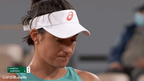 A Woman Wearing A White Visor With An Asics Logo On It Looks Down GIF