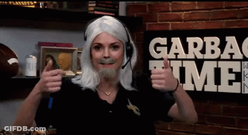 A Woman Wearing A Wig And A Headset Gives A Thumbs Up In Front Of A Garbage Time Sign GIF