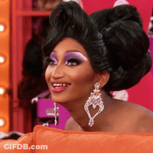Woman Smiling With Wig And Heart Earrings GIF