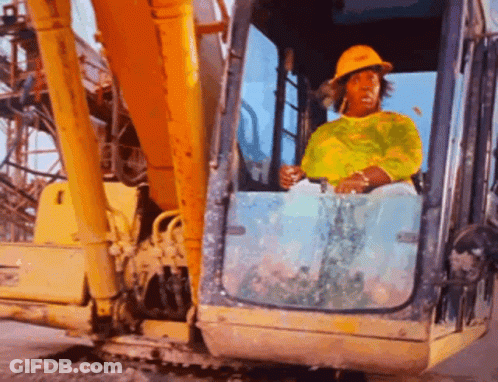 A Woman Wearing A Yellow Hard Hat Is Driving A Large Yellow Excavator GIF