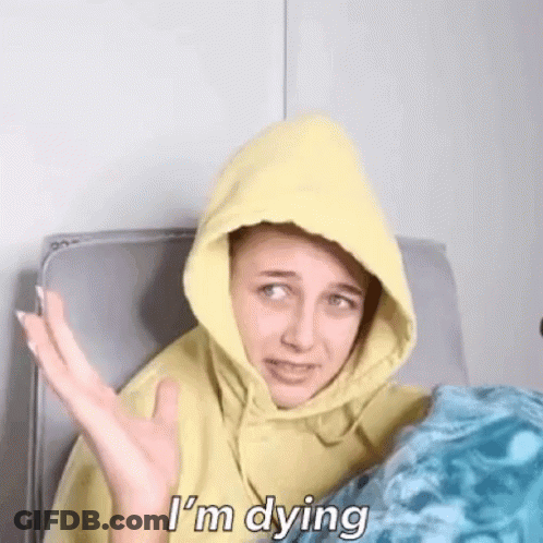 A Woman Wearing A Yellow Hoodie Is Sitting On A Couch And Says `` I 'M Dying '' . GIF