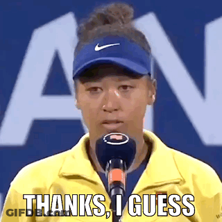 A Woman Wearing A Yellow Jacket And A Blue Hat Is Talking Into A Microphone And Saying Thanks , I Guess . GIF