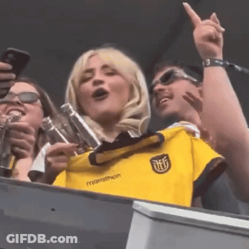 A Woman Wearing A Yellow Marathon Shirt Is Singing GIF