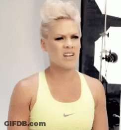 A Woman Wearing A Yellow Nike Sports Bra Is Making A Funny Face . GIF