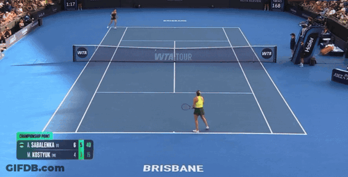 A Woman Wearing A Yellow Nike Tank Top Stands In Front Of A Scoreboard GIF