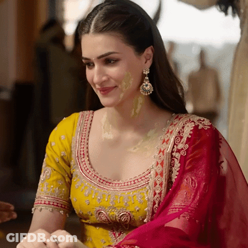 A Woman Wearing A Yellow Top And A Red Dupatta Smiles GIF
