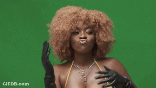 A Woman Wearing A Yellow Top And Black Gloves Is Making A Funny Face GIF