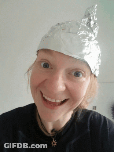 A Woman Wearing An Aluminum Foil Hat Smiles At The Camera GIF