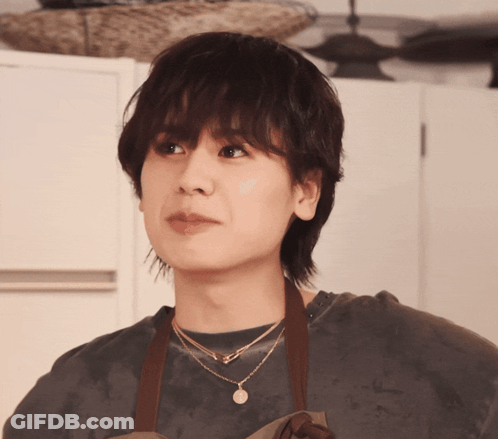 A Woman Wearing An Apron And A Necklace With The Letter A On It GIF