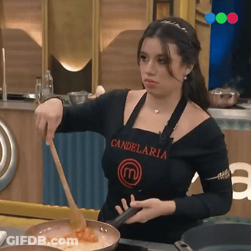A Woman Wearing An Apron That Says Candelaria Is Stirring Food In A Frying Pan GIF