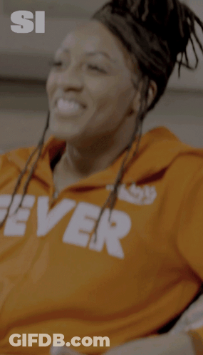 A Woman Wearing An Orange Hoodie With The Word Fever On It GIF
