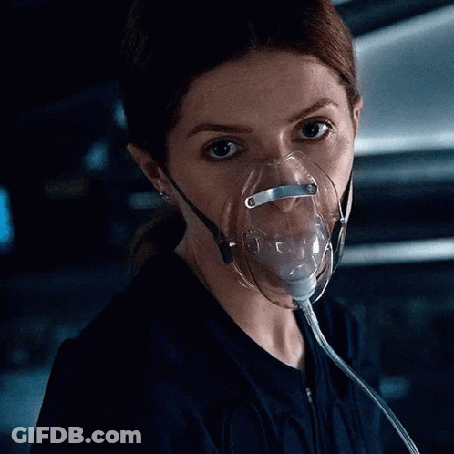 A Woman Wearing An Oxygen Mask Is Looking Down At Something . GIF